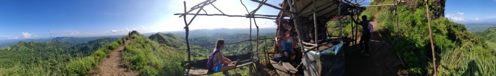 Hikers resting in a shack, drinking water, mountain views